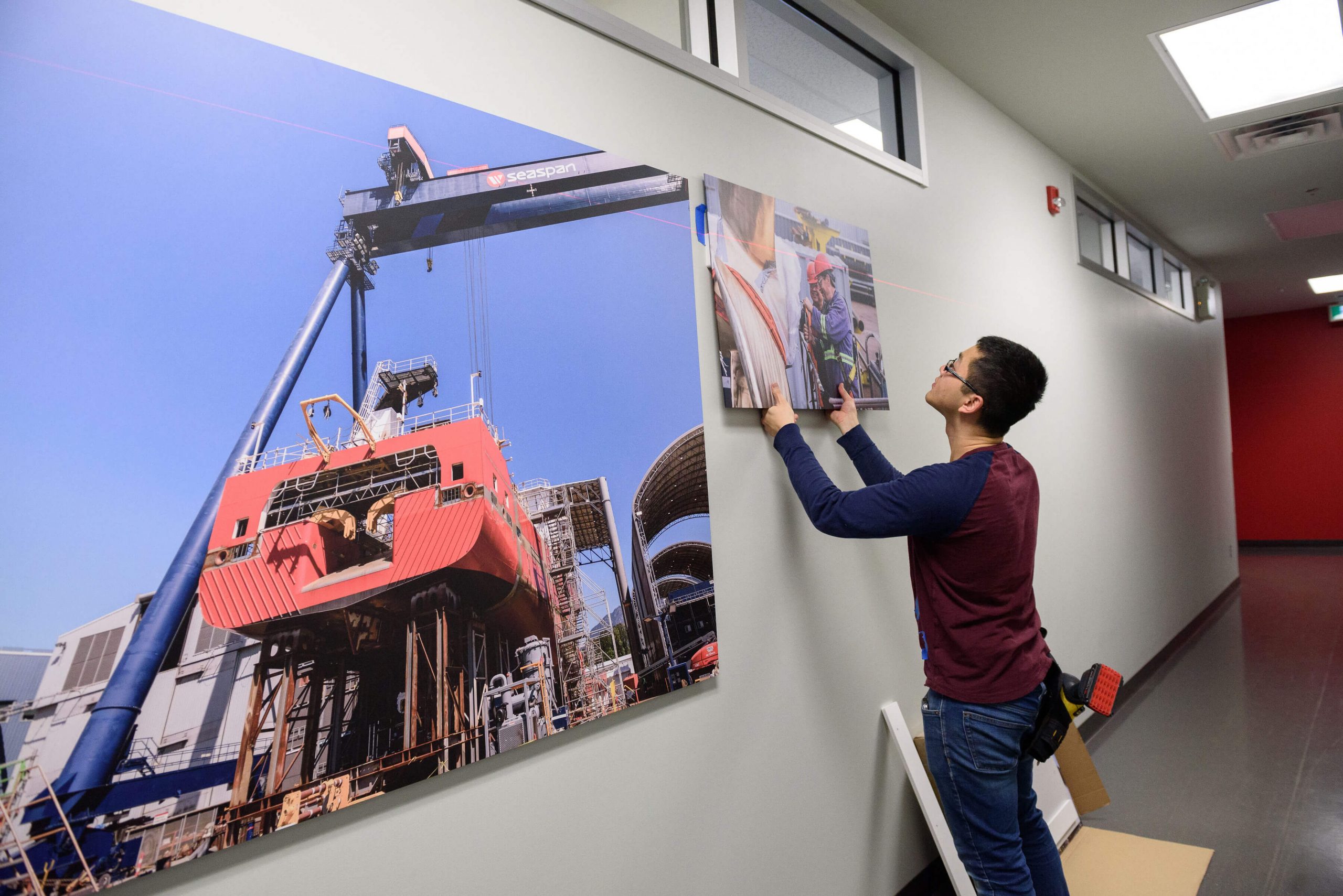Man installing a printed image on a wall