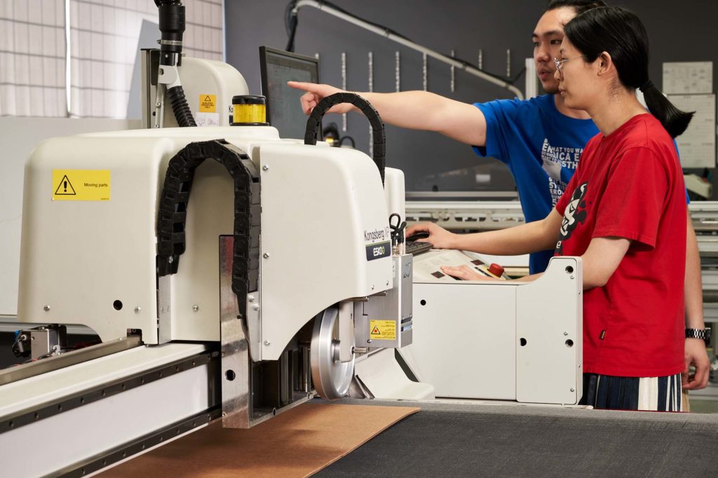 employees reviewing files on a digital cutter